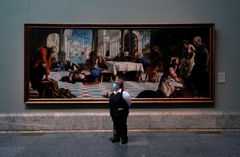 An employee stands next to Tintoretto's painting 'Christ washing the disciples' feet' as the Prado museum reopens to public under strict social distance measures in Madrid, Spain, June 6. REUTERS/Juan Medina